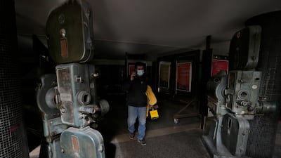 A man passes next to old movie projectors placed outside a theatre in Hamra Street. The projectors were used in the past at the movie theatre once known as Saroula.